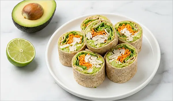 Wrap froid guacamole poulet et crudités coupé en roulés sur assiette blanche