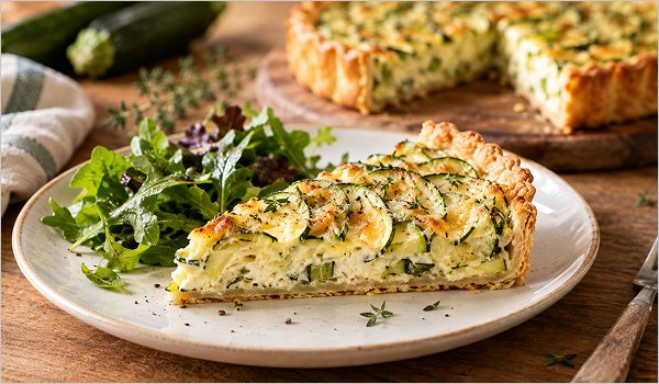 Part de tarte aux courgettes servie avec une salade verte
