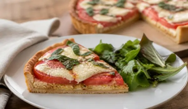 Part de tarte tomate mozzarella servie avec une salade verte au vinaigre balsamique
